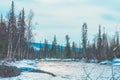 Landscape with river running through winter forest. Blue sky reflecting in shiny water, melting snow. Early spring Royalty Free Stock Photo