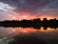 The landscape of the river after the storm during the summer evening at sunset, the reflection in the water, the dark dramatic Royalty Free Stock Photo