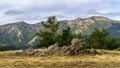 Landscape of rocks with green plants, dramatic sky with clouds and distant mountains Royalty Free Stock Photo