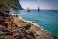 Landscape of rocky turkish beach with ships on horizon in Alanya. Scenery sea and mountains in sunny summer day at Turkey. Royalty Free Stock Photo