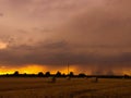 Landscape of rolled haystacks on a field under a cloudy sky during a beautiful sunset in the evening Royalty Free Stock Photo