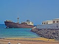 Landscape with a rusty broken large ship stranding offshore in the ocean