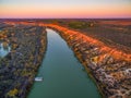 Landscape of sandstone cliffs over Murray RIver and moored houseboat at sunset.