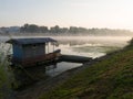 Landscape with Sava river and fishing hut and moored boats during beautiful foggy autumn morning Royalty Free Stock Photo