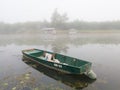 Landscape with Sava river and moored boat in water and fishing huts in fog during foggy autumn morning Royalty Free Stock Photo