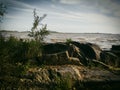 Landscape scene of a beach full of rocks and the horizon over water below blue sky with clouds. Royalty Free Stock Photo