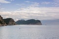 Landscape scenery of coastal island under forest, calm sea water and blue cloudy sky on the horizon. Spring or summer nature Royalty Free Stock Photo