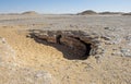 Barren rocky desert landscape in hot climate with cave entrance Royalty Free Stock Photo