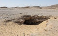 Barren rocky desert landscape in hot climate with cave entrance Royalty Free Stock Photo