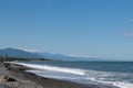 Seascape with waves, rocky shore and mountains in the distance. Royalty Free Stock Photo