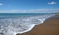 Landscape with sea, surf, sandy beach and high mountains at far Royalty Free Stock Photo