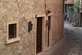 Landscape shot of an alley with a gray wall with brown doors, fenced window