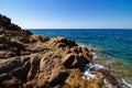 Landscape shot of large bedrocks in an open blue sea with a clear sunny blue sky