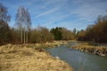 Landscape shot with a small, calm river that flows calmly in the winter against barren trees and dry grass Royalty Free Stock Photo