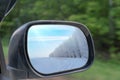 Landscape in the sideview mirror of a car, on road countryside. In the side mirror of the car is reflected winter landscape snow Royalty Free Stock Photo