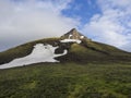 Landscape with snow capped mountain peak pyramide shape in central highlands Iceland, blue sky white clouds, golden light