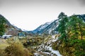 A landscape of a snow capped valley with trees and houses. Mountain with snow capped peaks and blue sky in the background Royalty Free Stock Photo