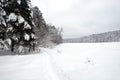 Landscape with snow-covered path on the edge of the forest and frozen river on a cloudy winter day Royalty Free Stock Photo
