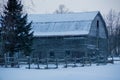 Landscape of snowy old grey gambrel barn with icicles