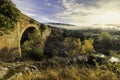 landscape with stone bridge over stream with green and yellow plants. Dramatic sky with clouds. Toledo, Spain, Europe Royalty Free Stock Photo