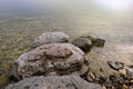 Landscape with a stony shore on the lake. Large stones in clear clear water.