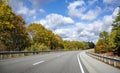 Landscape with a stretching highway road framed by autumn scenic maples and cloudy skies in Massachusetts Royalty Free Stock Photo