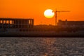 Landscape of sun rising over the construction site with crane in the sea in the morning in Dammam, Kingdom of Saudi Arabia Royalty Free Stock Photo