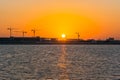 Landscape of sun rising over the construction site with crane in the sea in the morning in Dammam, Kingdom of Saudi Arabia Royalty Free Stock Photo
