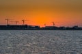 Landscape of sun rising over the construction site with crane in the sea in the morning in Dammam, Kingdom of Saudi Arabia Royalty Free Stock Photo