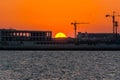 Landscape of sun rising over the construction site with crane in the sea in the morning in Dammam, Kingdom of Saudi Arabia Royalty Free Stock Photo