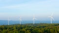 Landscape sun set shot of Wind turbines farm on the green grass field with clear blue sky and mountain at the background. Royalty Free Stock Photo