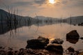 Landscape of the sun shining through cloudy sky over the lake with crystal clear water and mountains during sunrise with group of