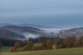 Landscape in the sunrise in the fog in the morning with meadow field forest tree mountains in the background near Grafenau in the