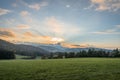 Landscape and sunset with meadow field forest tree mountains near Grafenau at Bavarian Forest with clouds and sunrays, Germany