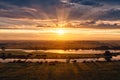 Sunset over the field and the river. The rays of the solsts through the clouds. Royalty Free Stock Photo