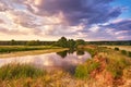 Landscape with sunset over river. Evening with Dramatic beautiful clouds on sky. Water reflection. Trees on riverbank. Weather Royalty Free Stock Photo