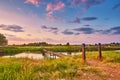 Landscape with sunset over river. Rural pedestrian old bridge. Evening with calm beautiful clouds on sky. Water reflection. Royalty Free Stock Photo