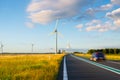Landscape during sunset with road, field and wind turbines. Windmills for energy production. Royalty Free Stock Photo