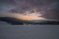 Landscape during sunset in winter with snow and ice and mountains in background near Grafenau in Bavarian Forest with clouds and s