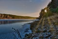 landscape sunset in the woods. winter pine forest on the banks of the frozen river Royalty Free Stock Photo