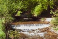 Landscape of swift mountain river with waterfall and stones among green trees