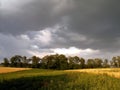 Landscape thunderclouds over the field and trees on a summer day Royalty Free Stock Photo