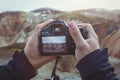 Travel photographer hands holding camera, taking photo of mountains