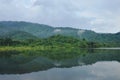 Landscape of tree and reflection on water surface in lake with mountain background Royalty Free Stock Photo