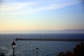 Seascape with two lampposts near the pier, a sailboat in the background against the coast, at sunset, Marseille, France Royalty Free Stock Photo