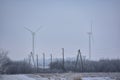 Landscape of two large white wind turbines in mist with electricity power lines at winter Royalty Free Stock Photo