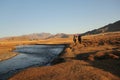 Landscape of a valley with a river and two horseriders with rocky mountains on a blurry background Royalty Free Stock Photo