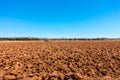 Landscape view of arable land, plowed red soil against blue sky. Royalty Free Stock Photo