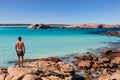 Landscape view of an athletic young man viewing the pristine white sands, crystal clear aqua water and granite boulders on a clear Royalty Free Stock Photo