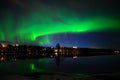 A landscape view of aurora borealis with a city scape under starry clear sky and reflection from lake water Royalty Free Stock Photo